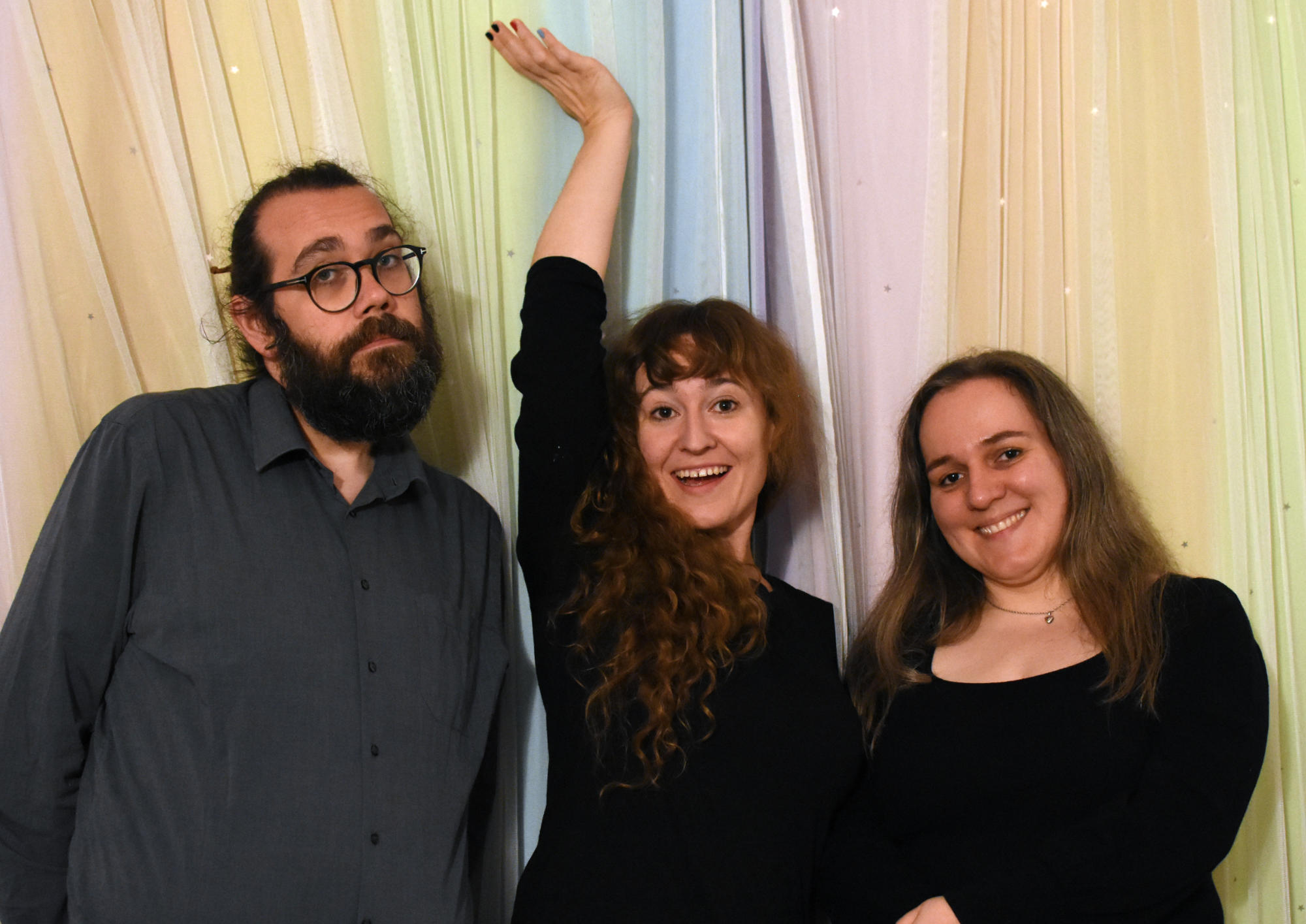 The BONMOTS, a singing trio, in front of a colorful curtain.